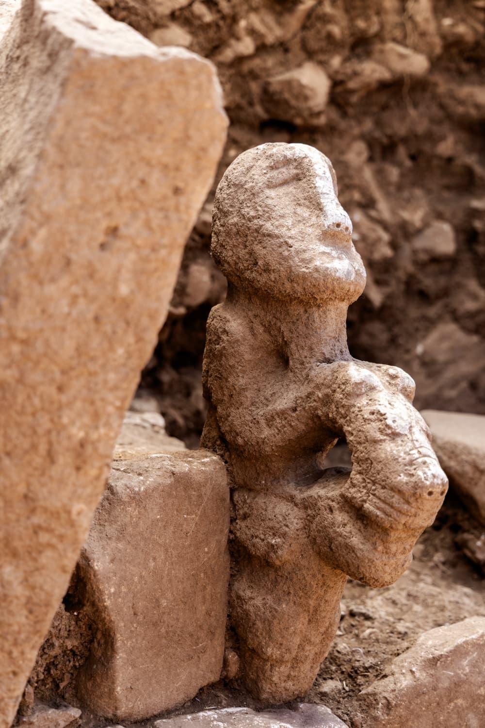 A carved rock statue depicting a human, most likelya man, sitting on the back of a leopard. A carved rock statue depicting a human, most likelya man, sitting on the back of a leopard.